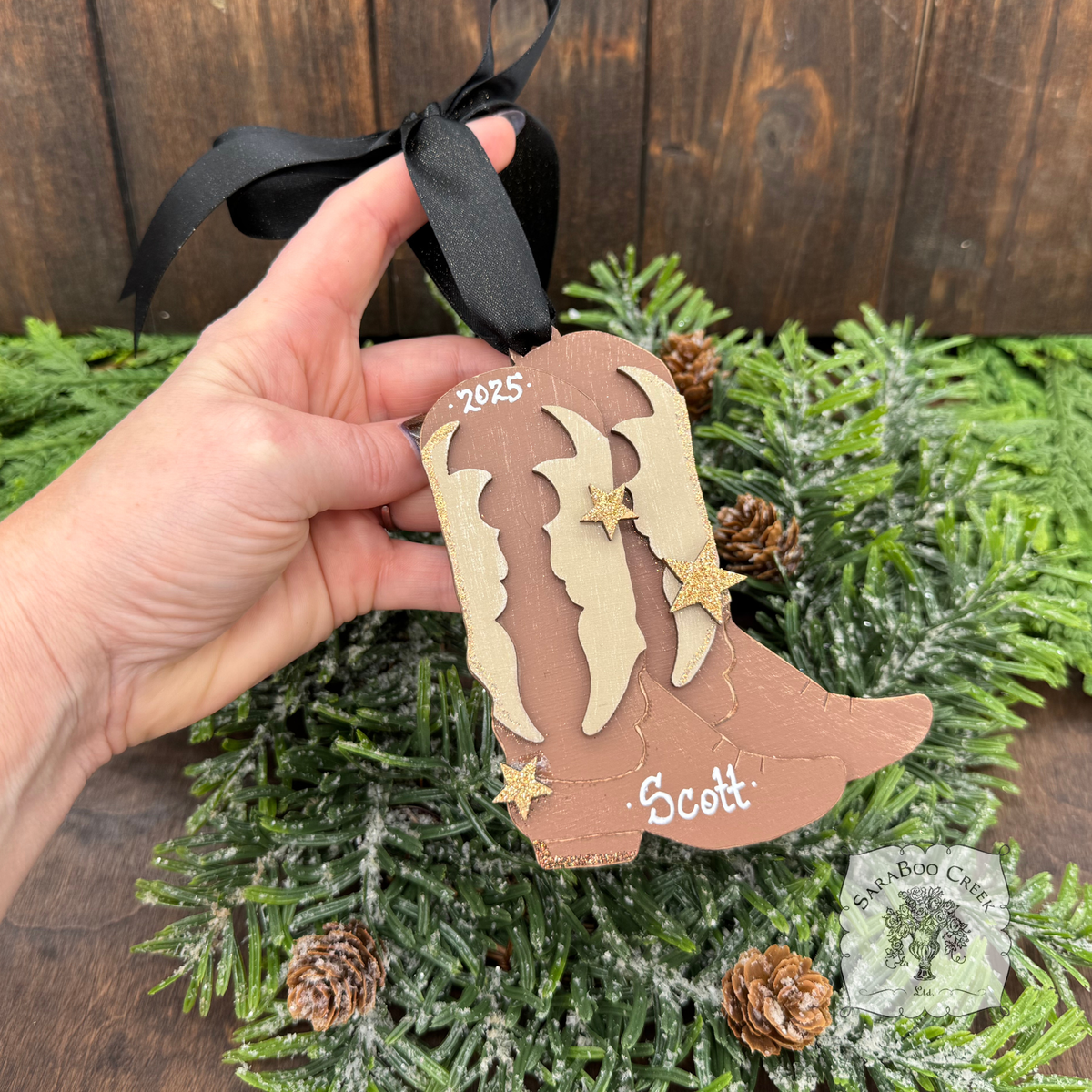 Decorative ornament shaped like a cowboy boot with 'Scott' and  they year on a Christmas tree.