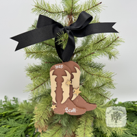 Decorative cowboy boot ornament with '2025' and 'Scott' on a Christmas tree.